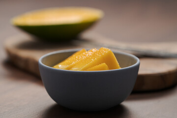 Fresh sliced mango in a ceramic bowl on walnut table