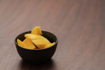 Fresh sliced mango in a ceramic bowl on walnut table