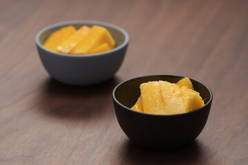 Fresh sliced mango in a ceramic bowls on walnut table