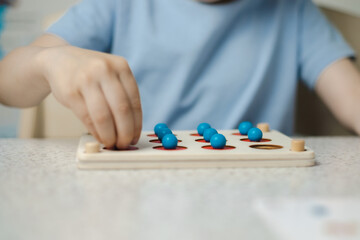 Close-up of the hands of an unrecognizable child playing a game for the development of memory and thinking. Wooden ecological toys. The concept of children's education.