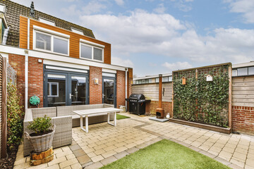 Neat paved patio with sitting area and small garden near wooden fence