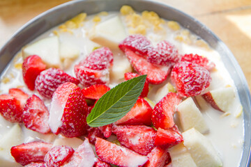 Cornflakes with oat milk and fruit - apple, pear and strawberries decorated with mint leaf
