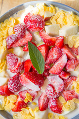 Cornflakes with oat milk and fruit - apple, pear and strawberries decorated with mint leaf