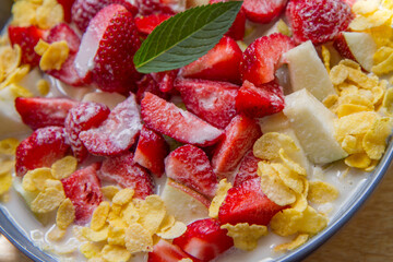 Cornflakes with oat milk and fruit - apple, pear and strawberries decorated with mint leaf