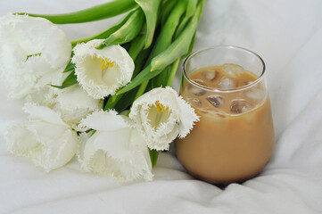 Obraz na płótnie Canvas bouquet of beautiful white tulips with iced coffee