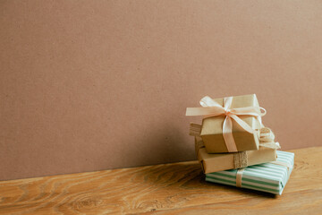 Stack of gift boxes on wooden table. brown wall background