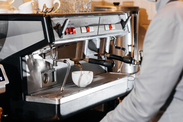 Close-up of a masked bartista preparing delicious delicious coffee at the bar in a coffee shop. The work of restaurants and cafes during the pandemic.
