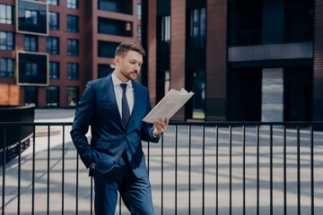 Boss reading newspaper in front of corporate building