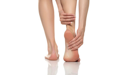 Foot pain in women on a white studio background. Pain concept