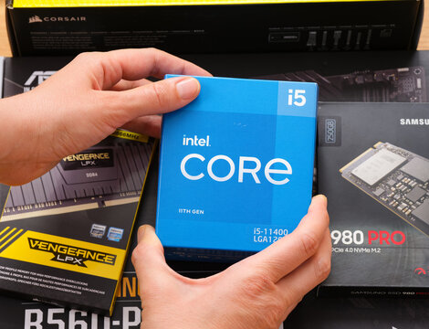 Tambov, Russian Federation - April 07, 2022 A woman hands holding box with an Intel Core i5 11400 CPU over other boxes with brand new components in them for building a new PC. 