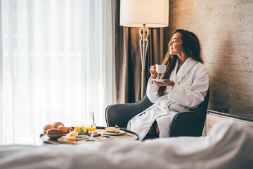 Woman eating breakfast in the hotel room. Room service breakfast in hotel room. - obrazy, fototapety, plakaty