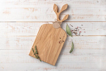 square wooden cutting board with a handle shaped leaves and spices on a white background. mockup with copy space for text, top view