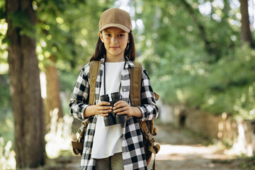 Young girl scout exploring parks with rucksack and binoculars