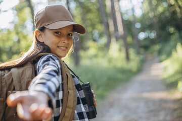 Portrait of young girl traveler in woods passing her hand into the camera