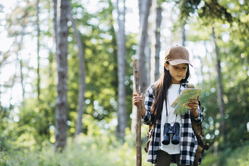 Girl looking at the map while walking in the forest