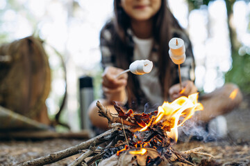 Girl scout frying marshmallows on fire at the woods