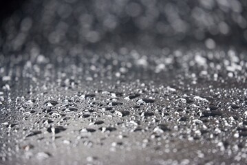 Blurred many rain droplets on a black leather with bokeh light and dark background 