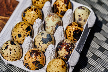 Top view and bokeh effect with a box of fresh quail eggs with a speckled shell.