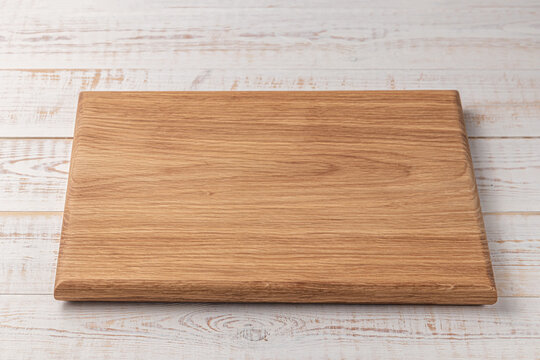 rectangular cutting board on a white wooden table. mockup of a food background with copy space, side view