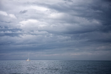 Sailing boat on sea under storm clouds