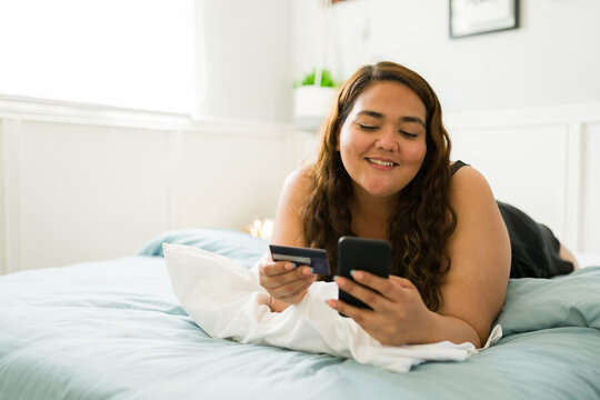 Plus size woman buying clothes online while in bed