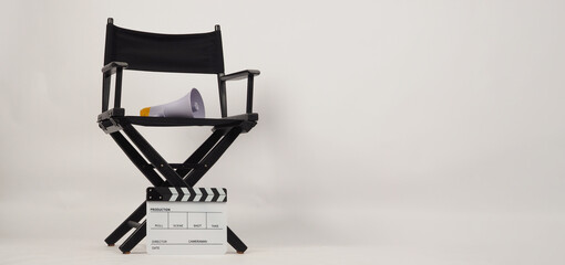 Black director chair with megaphone on the chair and white clapper board on white background.