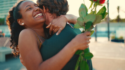 Close-up of young happy man and woman joyfully hugging when meeting on the embankment, man gives...