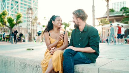 Closeup portrait of happy interracial couple eating ice cream in urban city background. Close-up of...