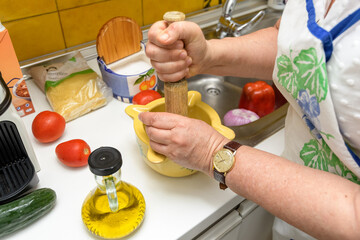 Housewife making a fideua. Breaking the garlic with the dough and the mortar to make aioli sauce - obrazy, fototapety, plakaty