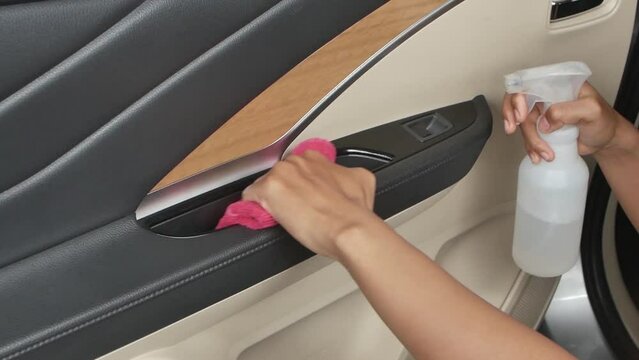 Cleansing car interior and spraying with disinfection liquid. Hands in rubber protective glove disinfecting vihicle's door handle for protection against virus disease