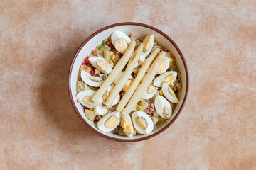 Overhead view of a country salad with white asparagus on an abstract studio background. Summer and healthy recipes.