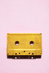 Obraz premium Retro audio cassette on pink. Old golden colour cassette tape.