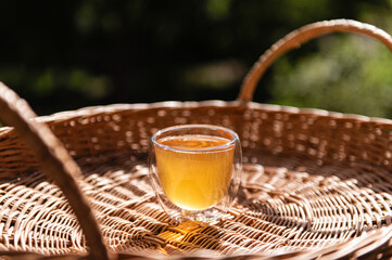 Tea mushroom, kombucha drink, home-made, refreshing drink in a glass cup, on a wicker tray in nature