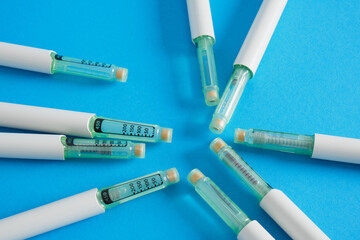 a lot of insulin syringe pens for diabetes treatment on blue background