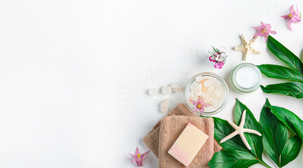 Spa composition with cream, soap, towel and salt on a white background. Top view, copy space.