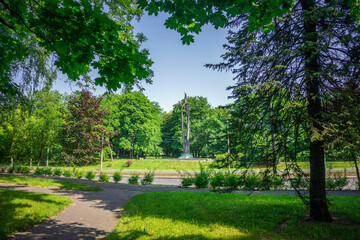 Rośliny i kwiaty w Parku Lotników w Krakowie. Widok na pomniek.