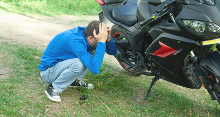 Depressed caucasian biker with a motorcycle.