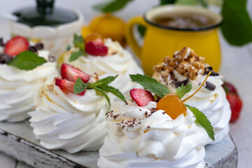 Pavlova meringue cakes with whipped cream and fresh strawberries, mint leaves. Selective focus.