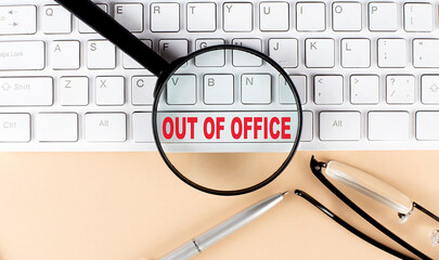 Text OUT OF OFFICE on keyboard with magnifier , glasses and pen on beige background - obrazy, fototapety, plakaty