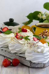 Pavlova meringue cakes with whipped cream and fresh strawberries, mint leaves. Selective focus.