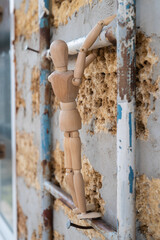 Wooden mannequin close-up climbing on ladder in the construction, vertical photo 