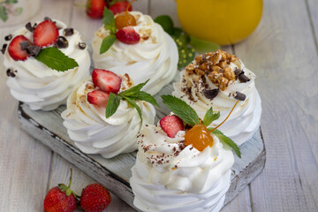 Pavlova meringue cakes with whipped cream and fresh strawberries, mint leaves. Selective focus.