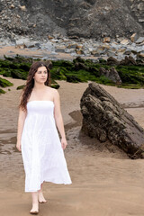 woman walking on the beach in a white dress