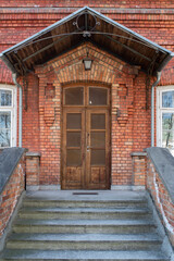 Wooden doors,  front entrance to old red brick house with gray stairs