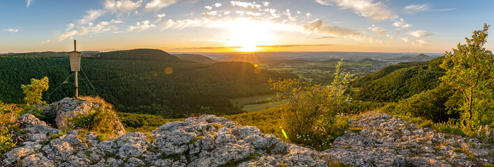High-res panorama shot of scenic rock ledge and summit cross at sunset in the Swabian Jura in...