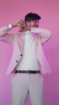 Winner dance. Success celebration. Party joy. Neon light happy relaxed guy in glasses stylish suit enjoying fun movements isolated on pink color vertical background.
