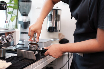 Closed up Asian Young barista woman is wearing apron and brewing coffee with machine for customers order in cafe and coffee shop. Start up small cafe business and technology Concept.