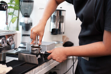 Fototapeta na wymiar Closed up Asian Young barista woman is wearing apron and brewing coffee with machine for customers order in cafe and coffee shop. Start up small cafe business and technology Concept.