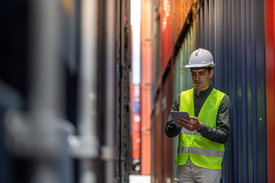 Container operator holding a tablet for his daily inspection of the container while walking in container yards.