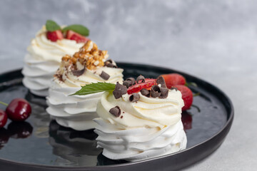 Pavlova meringue cakes with whipped cream and fresh strawberries, mint leaves. Selective focus.